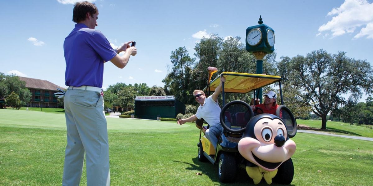 Two people posing near a Mickey Mouse golf cart at Walt Disney World Resort