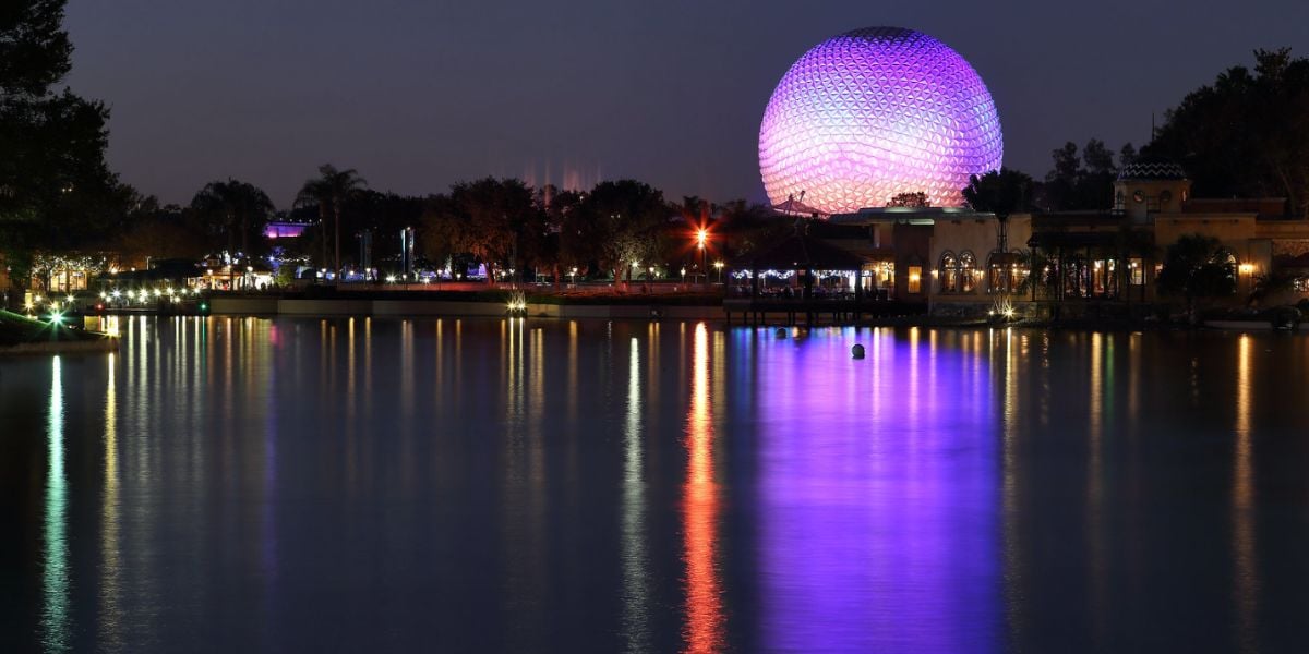 Spaceship Earth lit over the EPCOT World Showcase Lagoon at night.