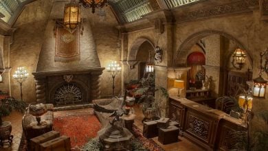 A grand, old-fashioned hotel lobby with ornate furniture, a large fireplace, antique decor, and a red-patterned rug exudes an abandoned, eerie atmosphere reminiscent of the Tower of Terror.