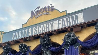 The entrance to Knott’s Scary Farm is decorated with black bows and purple drapes. A large sign reads "Knott’s Scary Farm" beneath the Knott’s Berry Farm sign on the yellow building.