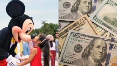 A person in a Mickey Mouse costume greets a young girl outdoors on the left; on the right, there are several U.S. $100 bills spread out.