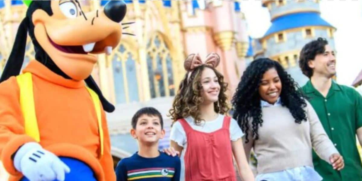 A person in a Goofy costume stands beside a smiling group of four, including two children and two adults, enjoying their lightning lane access in front of a fairytale castle at an amusement park.