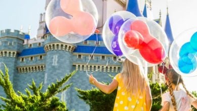 kids with balloons in front of cinderella castle in disney world's magic kingdom