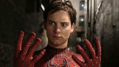 A young man in a Spider-Man suit stands in a dimly lit alley, looking down in surprise at his outstretched gloved hands. His expression is one of shock and disbelief.
