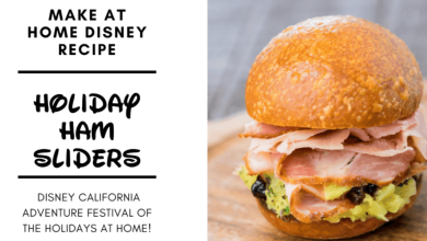 A close-up of a ham slider with lettuce and raisins in a round bun sits on a wooden board. Text beside it reads: “Make at Home Disney Recipe — Holiday Ham Sliders — Disney California Adventure Festival of the Holidays at Home!”.
