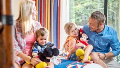 family sits on a bed in a disney world hotel room