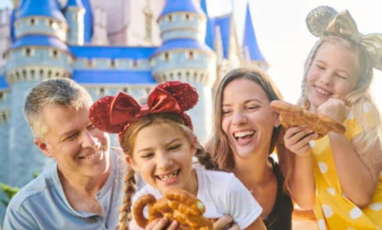 smiling family in front of Disney World's Cinderella Castle with Mickey-shaped pretzels