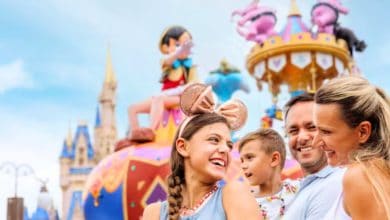 family at disney world's magic kingdom as festival of fantasy parade passes in the background