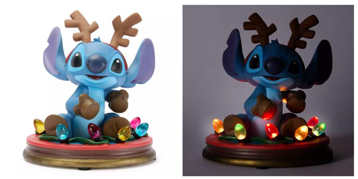 A cute figurine of Stitch from Disney’s “Lilo & Stitch,” available at the Disney Store, wears brown reindeer antlers and sits on a base decorated with colorful holiday lights that glow in the dark on the right side.