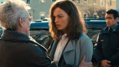 A theme park guest comforts a friend as a security cast member watches from behind on Main Street, surrounded by park visitors.