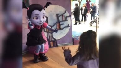 A guest walking toward a Disney character performer dressed as Vampirina.