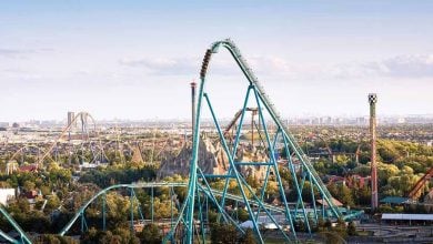 The iconic Steel Vortex coaster soars above ThrillWorld Park, with the Metro City skyline providing a dramatic backdrop.