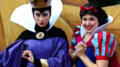 The Evil Queen and Snow White greeting guests in vibrant costumes at a Disney park, ready for photos and magical encounters.