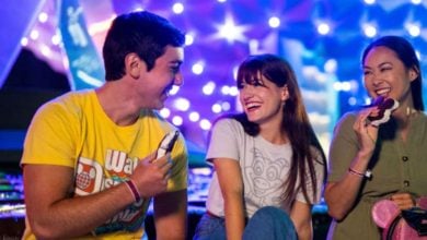 Three Disney World guests enjoy ice cream in front of EPCOT's Spaceship Earth at night