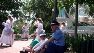 A Disney security guard kneeling next to guests watching a parade.