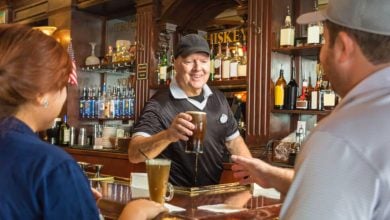 A Universal Bar bartender serves guests at the lively wooden bar, a popular hangout for Universal Orlando Resort fans.