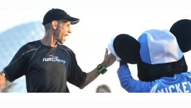 A runner shares a high-five with Mickey Mouse at a runDisney event, cheered on by fellow Disney fans.