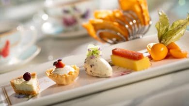 A magical dessert plate at Disney's Main Street Bakery, featuring whimsical pastries, fresh fruit, cream, and teacups nearby.