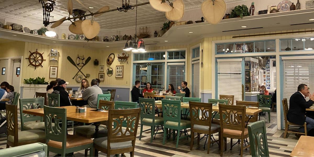 A lively Disney Vacation Club Resort restaurant with green and wooden chairs, nautical theming, and guests enjoying their meals.