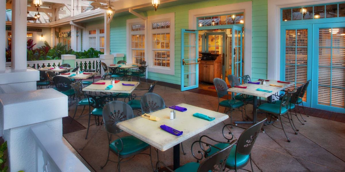 Outdoor patio at the original resort features teal chairs, white tables, turquoise doors, and fun napkins—ideal for DVC fans.