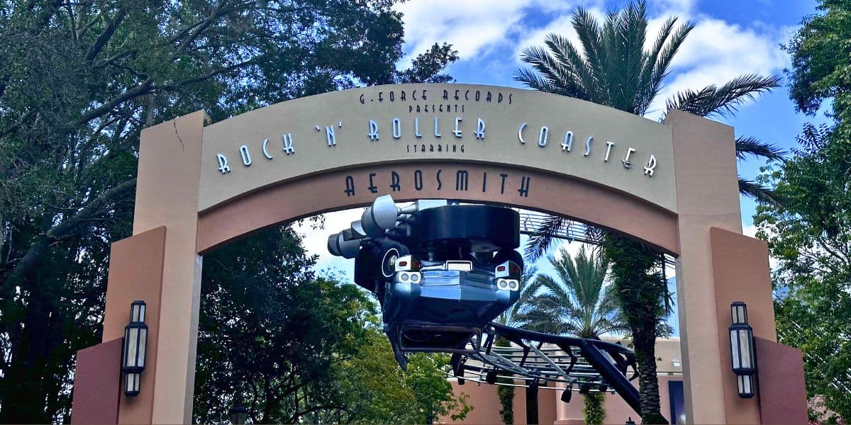 Rock 'n' Roller Coaster archway at Disney, featuring Aerosmith branding, coaster car, and palm trees in the backdrop.