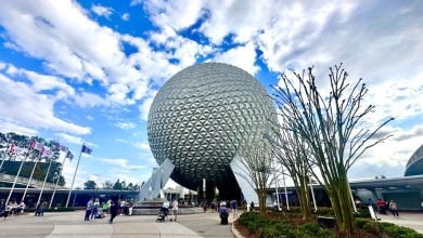 Spaceship Earth rises at EPCOT as guests stroll below, highlighting the park’s futuristic Disney magic beneath a lively sky.