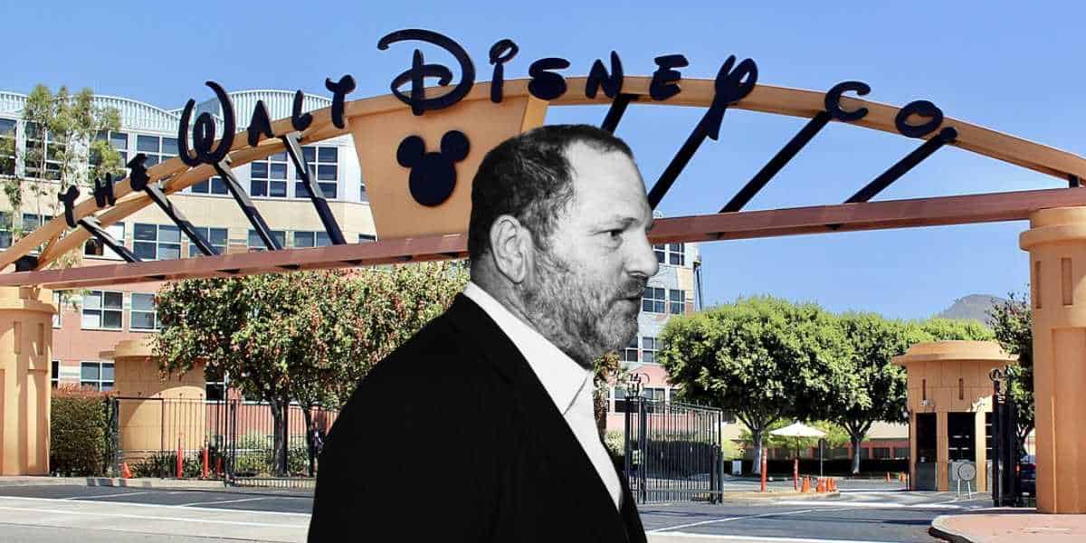 A guest in a suit stands outside the iconic Walt Disney Co. gate on a bright day, discussing ongoing Disney pension benefits.