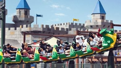 Guests thrill on the Dragon Coaster speeding past the iconic blue-roofed Fairy Tale Castle at Fantasyland Park at Dubai Parks and Resorts.