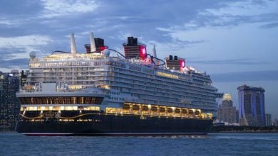 A glowing Disney Cruise Ship sets sail from the iconic Forever Port, city lights sparkling like a magical, theme park adventure.