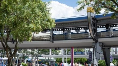 Guests walking underneath the Tomorrowland Transit Authority PeopleMover at the Magic Kingdom.