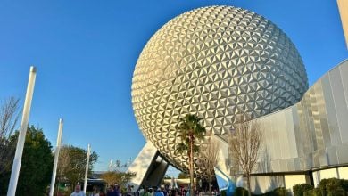 Spaceship Earth glowing at sunset in Epcot, with excited Disney guests enjoying the iconic park landmark under a clear sky.