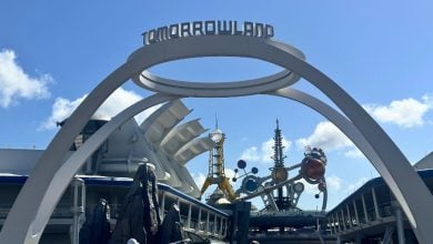 Tomorrowland’s entrance archway at Disney, showcasing sleek futuristic designs beneath a vivid blue sky.
