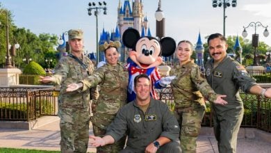 Mickey Mouse welcomes five uniformed military guests in front of Cinderella Castle at Disney World