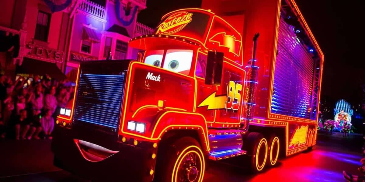 Mack from Cars glows with neon on Main Street during Disneyland's Paint the Night Parade as a guest jumps aboard, earning a ban.