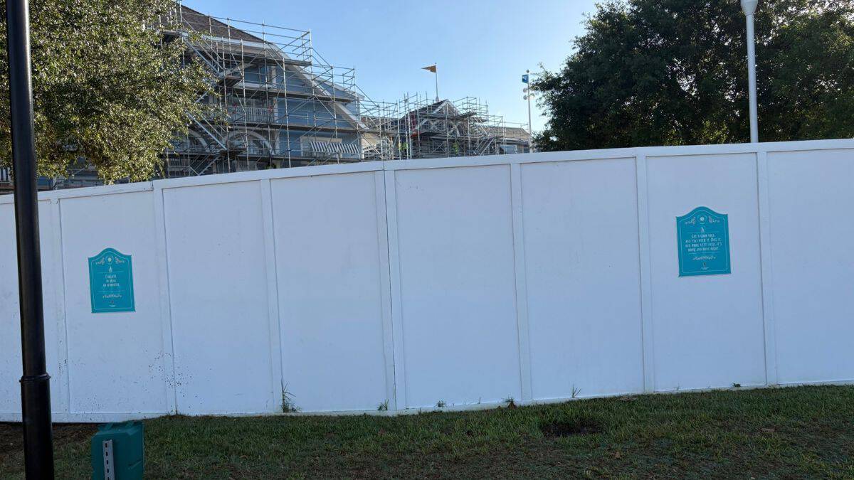 White construction fence and scaffolding outside Disney's Beach Club Resort, surrounded by trees and grass during refurbishment.