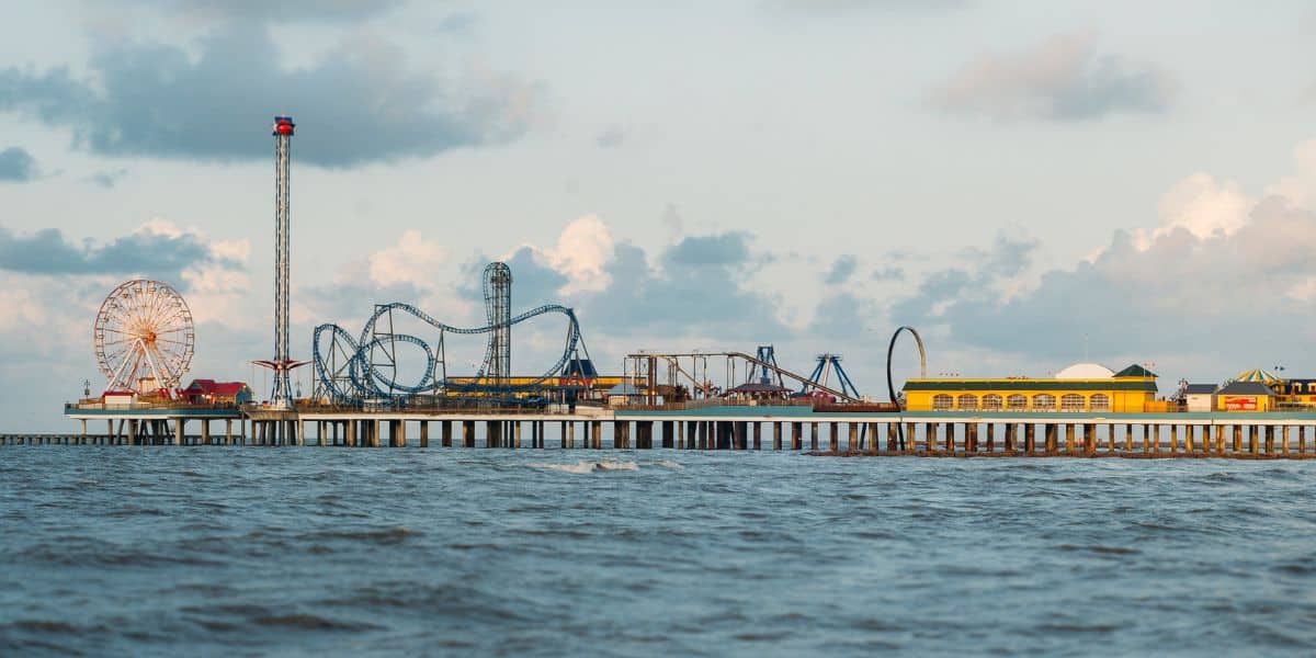 Galveston Island Historic Pleasure Pier with its iconic roller coaster and Ferris wheel, students reveling in seaside thrills.