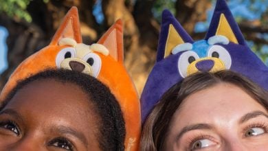Bluey and Bingo headbands peeking above the crowd, capturing the playful spirit of a family day at the theme park.