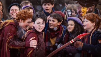 Kids bundled up for a snowy holiday festival cheer outside as one waves a bright red broomstick, winter magic all around.
