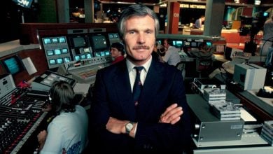 A dapper executive stands confidently in a fast-paced studio, surrounded by glowing screens like a control room at Universal Studios.