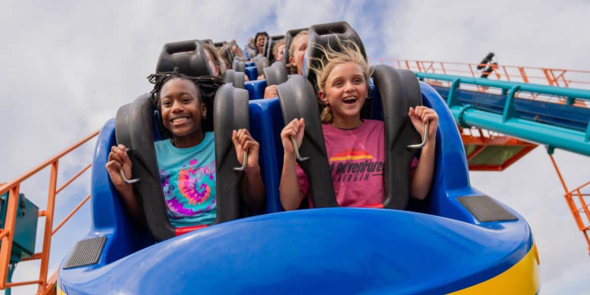 Visitors laughing on a Busch Gardens roller coaster under sunny Florida skies—catch summer’s top thrills with our exclusive ticket offer!.