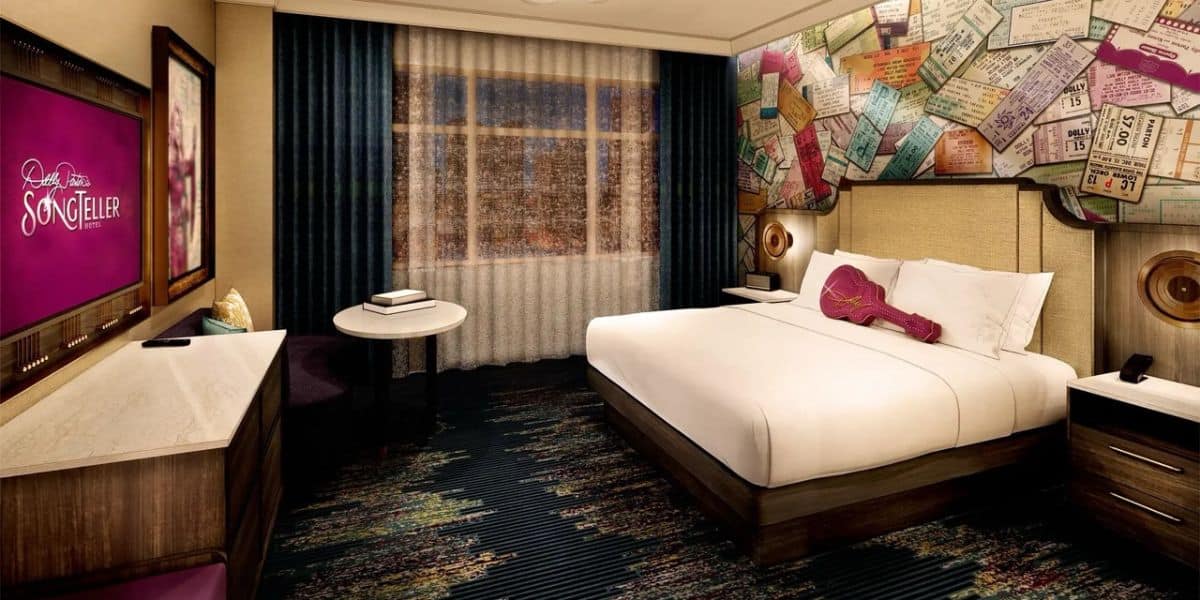 Rockstar-inspired king room with guitar pillow, bold music decor, flat-screen TV, work desk, and floor-to-ceiling curtained windows.
