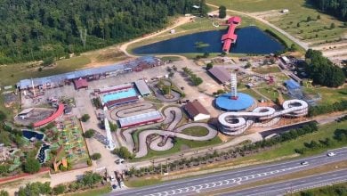 Aerial view of Fun Spot America Atlanta, showcasing go-kart tracks, lake, thrill rides, and attractions beside the highway.