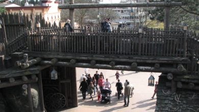 Guests stroll beneath the Frontierland wooden bridge at Disneyland Paris