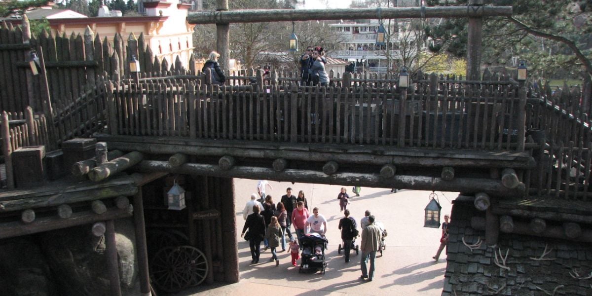 Guests stroll beneath the Frontierland wooden bridge at Disneyland Paris