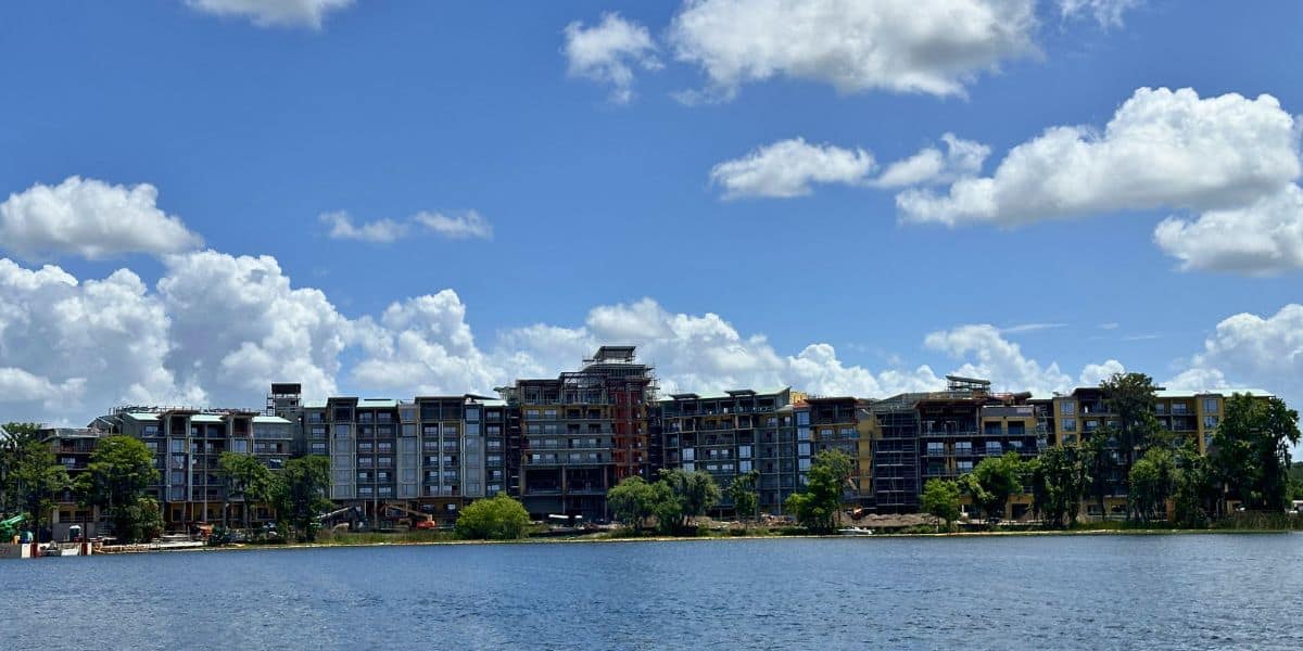Sleek new Disney Orlando Resort complex on a lakeside, set to open 2027 for magical vacations and easy guest reservations.