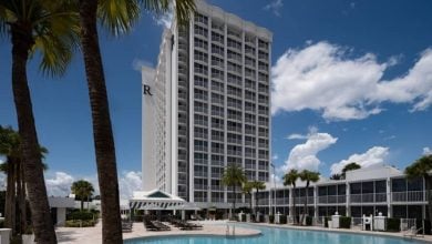 Grand resort hotel near waterpark, surrounded by palm trees, pools, sun loungers, and a vibrant sky—perfect for family fun.