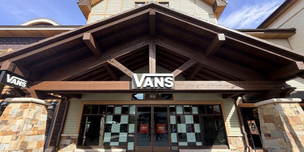 Vans storefront designed like a rustic chalet, featuring wooden peaks and stone pillars, inviting guests to shop in style.
