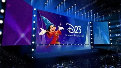 Sorcerer Mickey takes center stage with the iconic D23 logo, entertaining an excited crowd of Disney fans inside the lively arena at the Anaheim Show Floor.