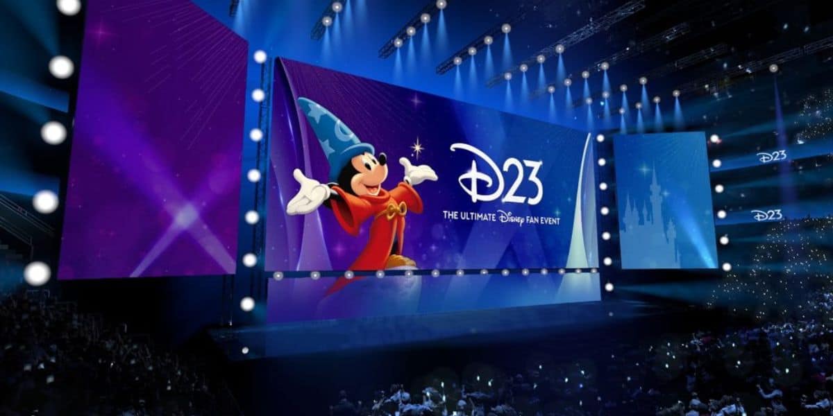 Sorcerer Mickey takes center stage with the iconic D23 logo, entertaining an excited crowd of Disney fans inside the lively arena at the Anaheim Show Floor.