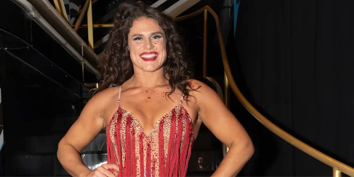 A dazzling performer in a red, glittery dress grins on the grand staircase, ready to greet guests at the show.
